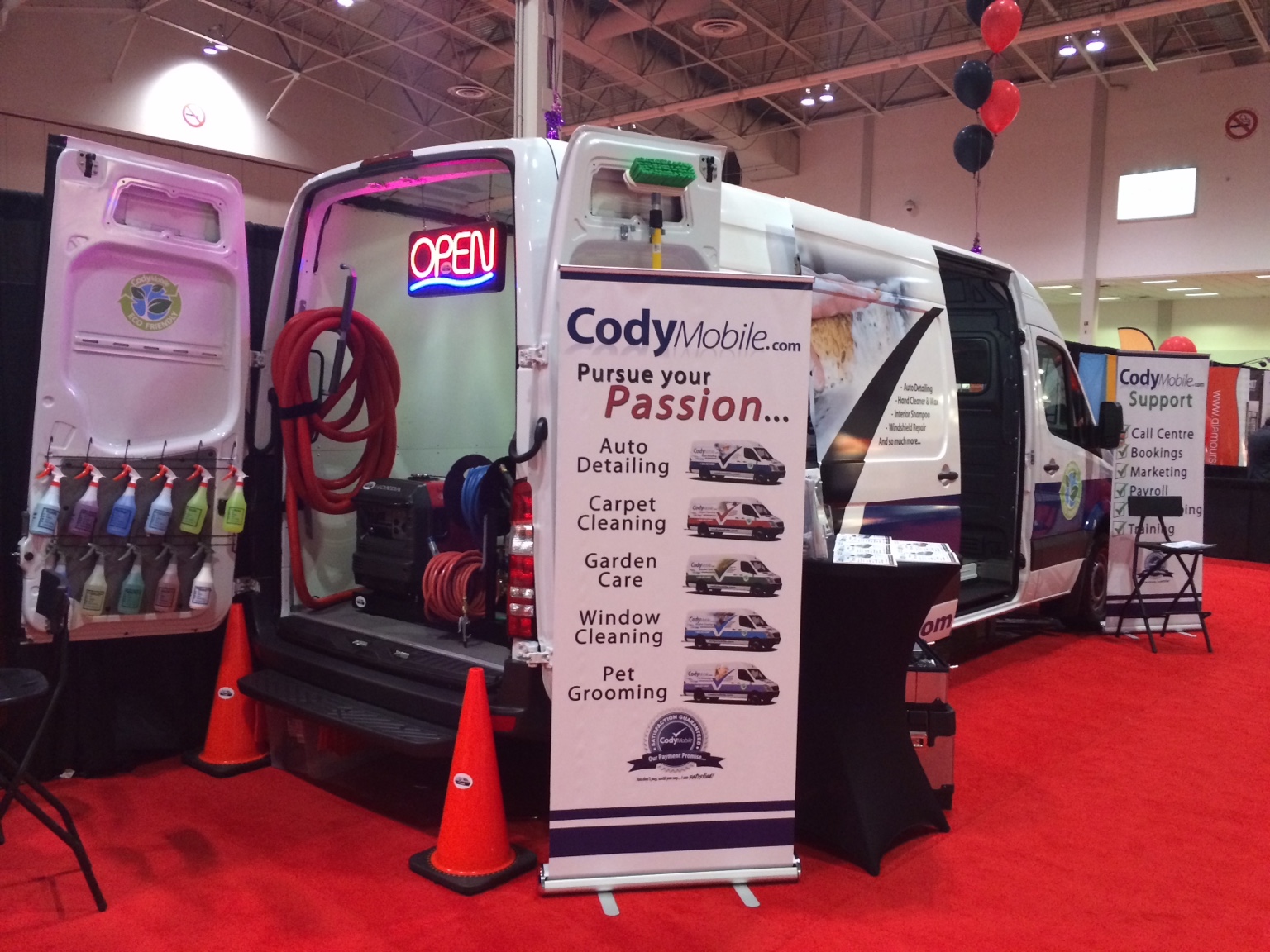 Cody Mobile van on display at an exhibition, with its rear doors open and original promotional banners