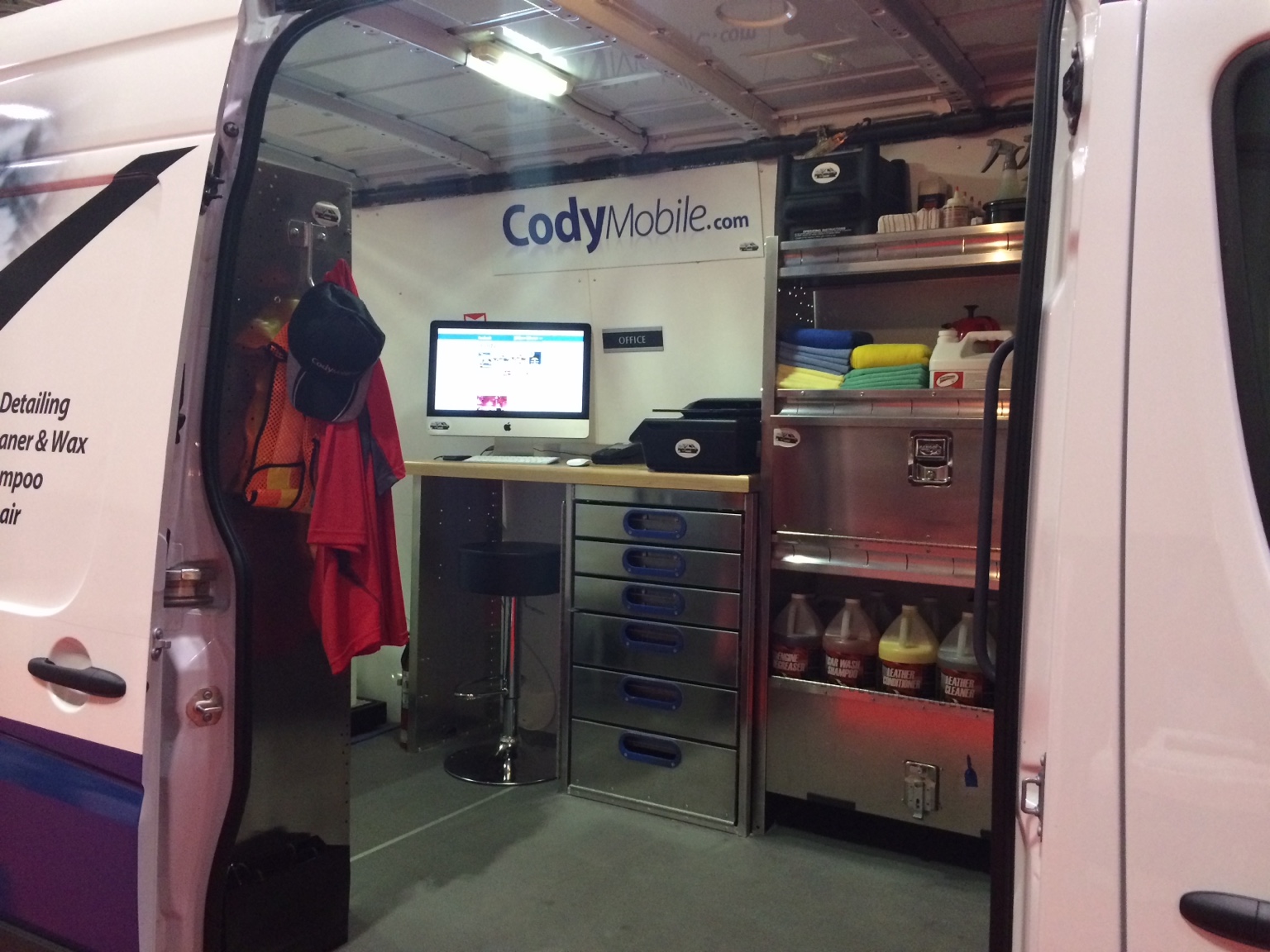 Inside a Cody Mobile van, showing a built-in desk, computer, storage drawers and detailing supplies